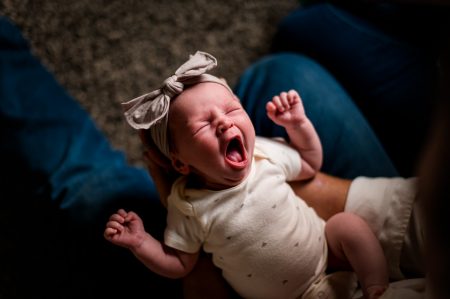 newborn yawns in her parents arms in Colorado family lifestyle session in their home