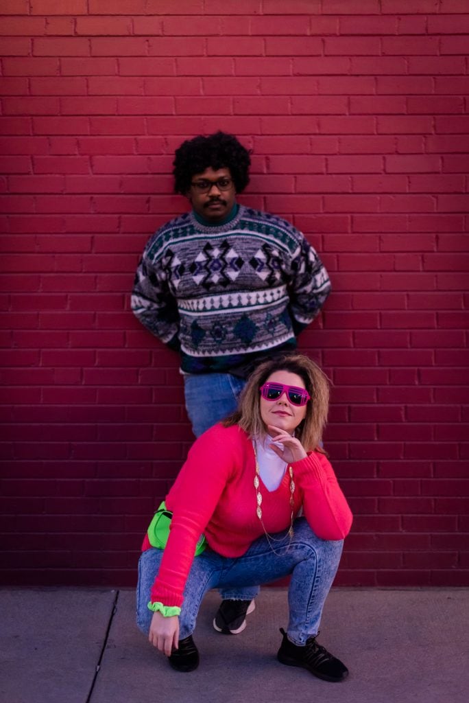 Couple poses together in Denver in 80s styled clothes for their awkward 80s engagement session