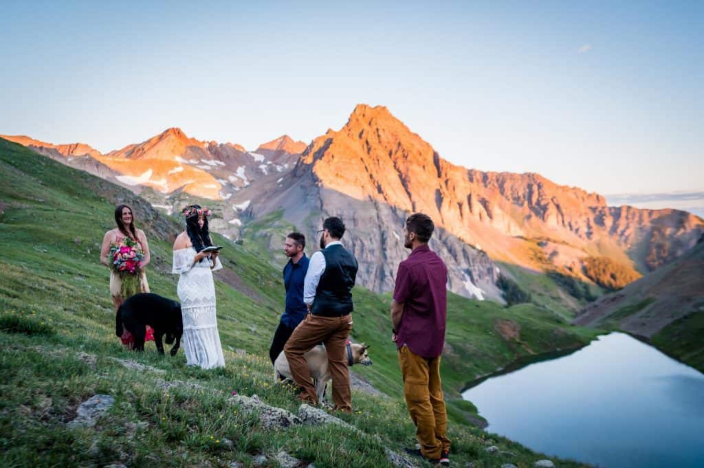 a couple reads their vows to each other at sunrise above blue lakes in ridgway with Dallas Peak in the background