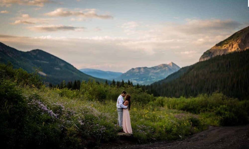 a couple embraces in the wildflowers at sunrise with Mt Crested Butte in the background for their adventure anniversary photography session.