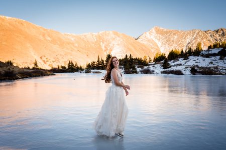 a bride ice skates on a frozen alpine lake at her elopement in Colorado
