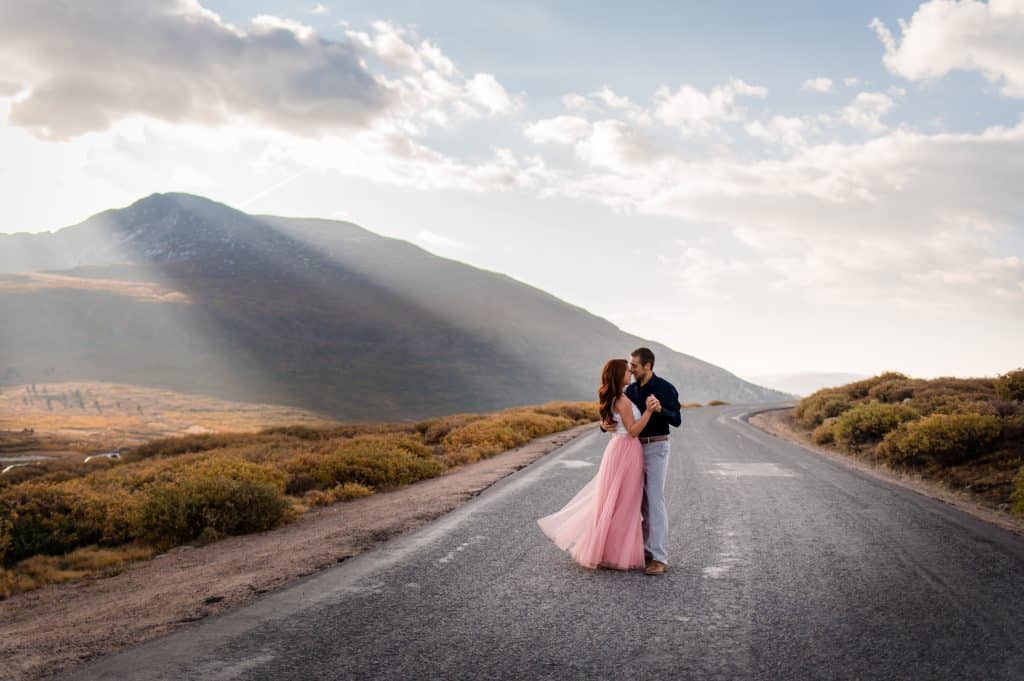A couple dances in the road together near Mount Bierstadt for their mountain adventure anniversary session on Guanella Pass at sunrise.