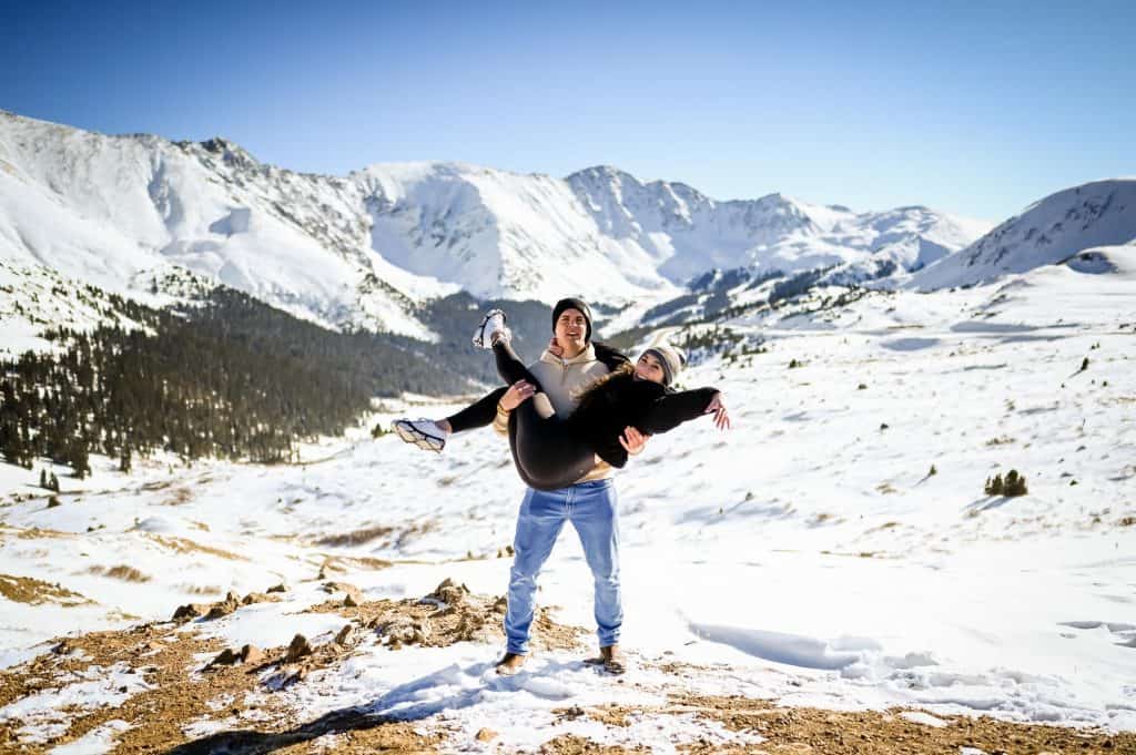 a couple celebrate their proposal of engagement on top of loveland pass in colorado