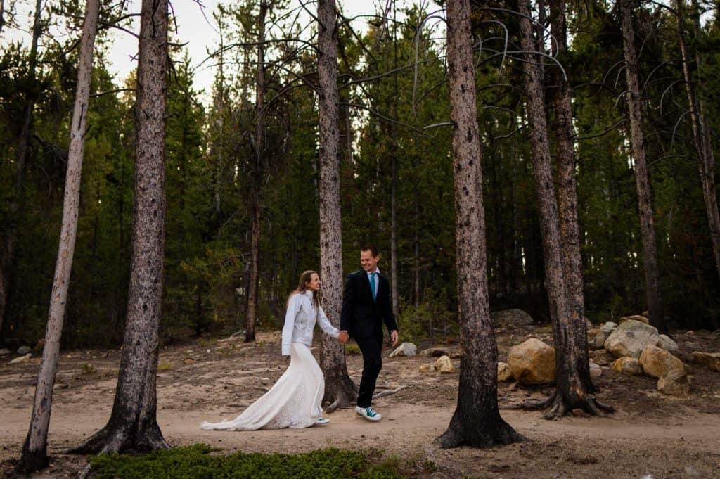 a couple hikes through tall pine trees together along a trail near Turquoise Lake in Colorado
