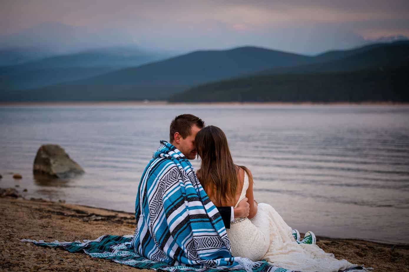 a couple lays on the beach together at an alpine lake in Colorado after their adventure elopement