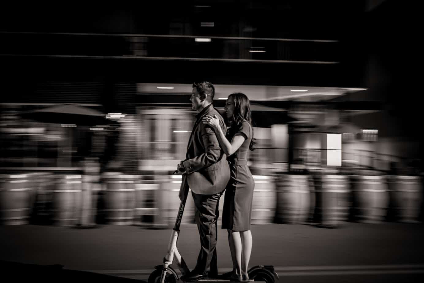 an lgbtq couple rides a scooter together through RiNo at night