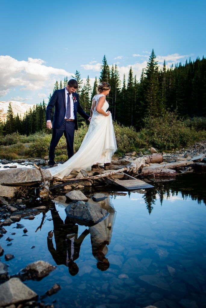 a couple crosses a creek together at their Breckenridge Elopement in Colorado