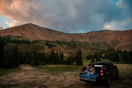 A couple snuggles in the back of their truck up a mountain 4x4 road in Colorado.