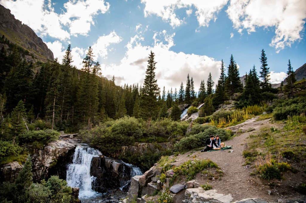 A couple has a picnic next to a waterfall during their adventurous elopement in Ouray, Colorado
