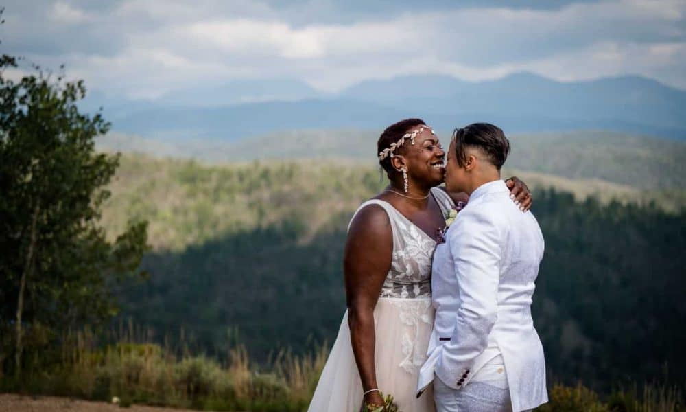 a bride kisses her bride's chin at their mountain wedding in Colorado