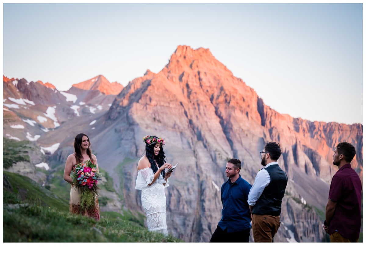 a couple exchanges vows underneath Dallas Peak alpenglow at their sunrise hiking elopement in Telluride