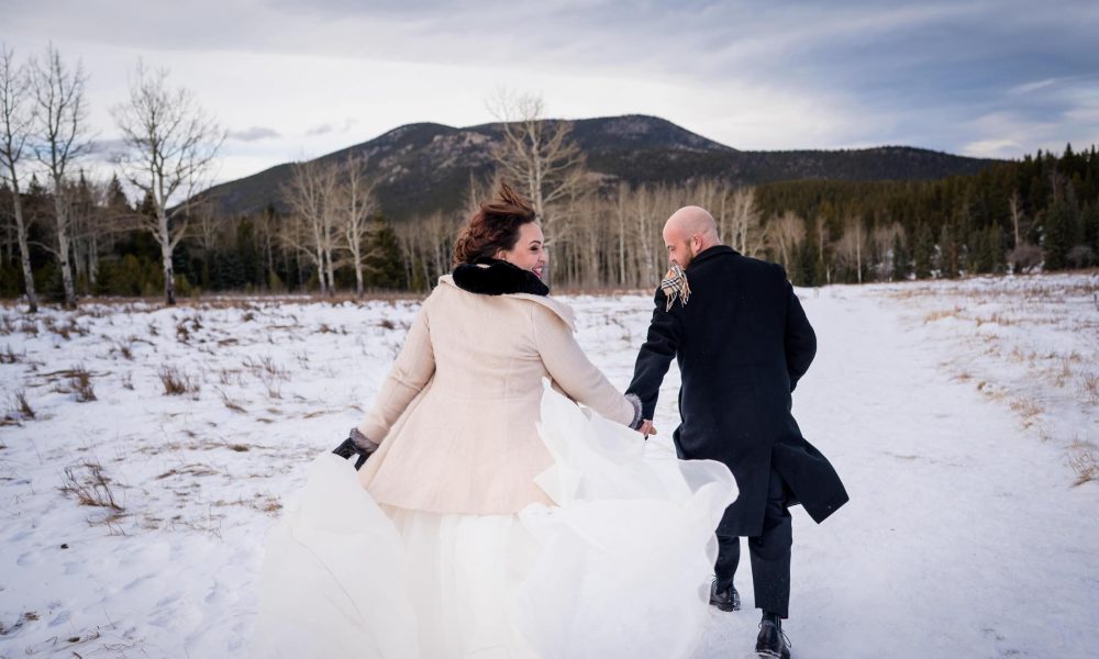 a couple runs down a snowy trail at their winter elopement in Colorado