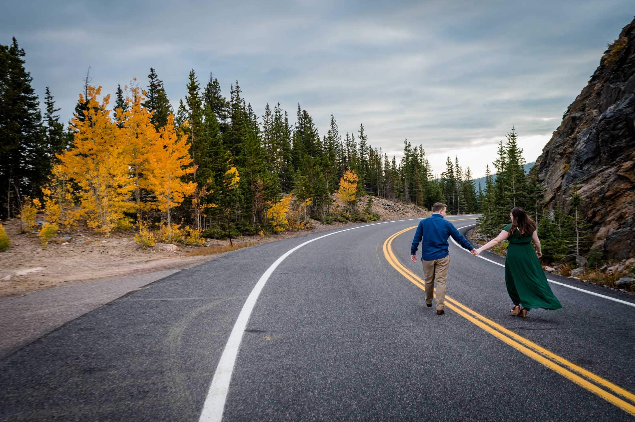 a couple runs down the road during their colorado mountain engagement photography session