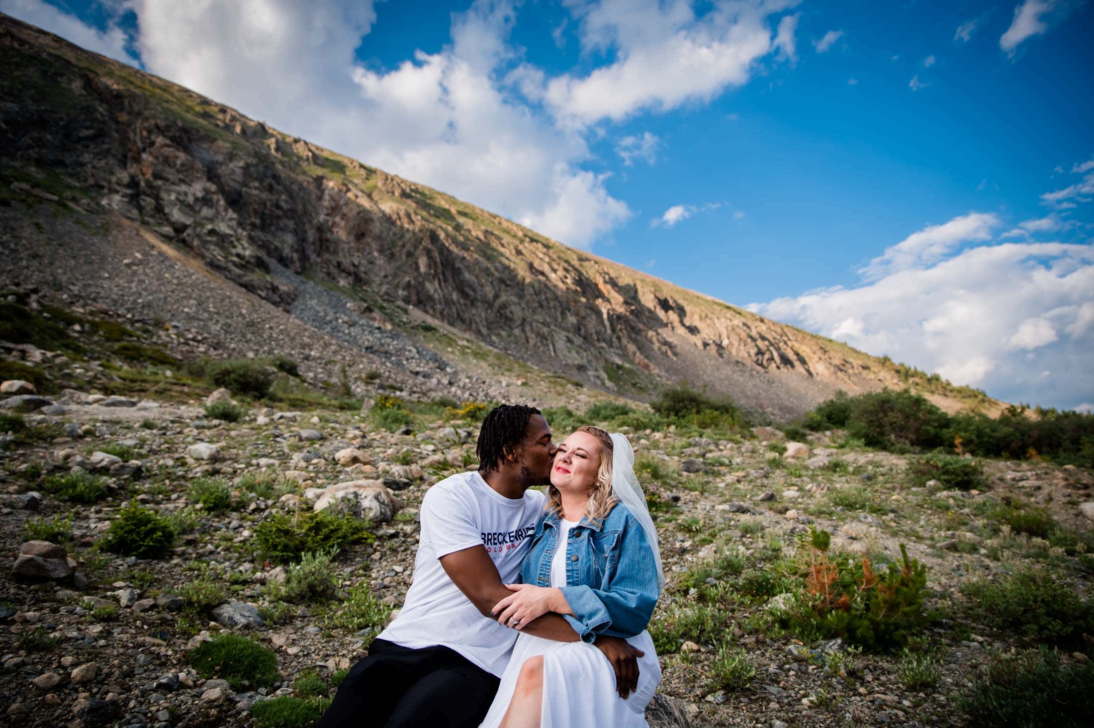a couple snuggles on a mountain side near Blue Lakes in Breckenridge after their elopement wedding ceremony