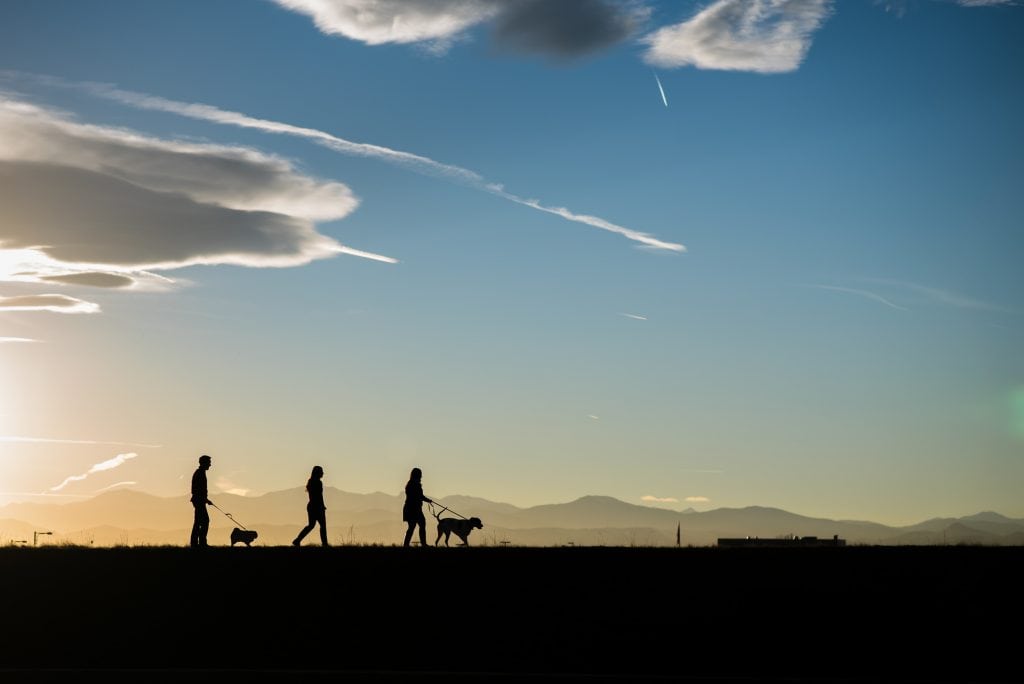 a family walks in tandem with a beautiful sunset mountain view behind them for their family adventure photography session in Colorado