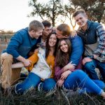 a family of adult kids and dad snuggle up on mom at their family photography experience in Colorado