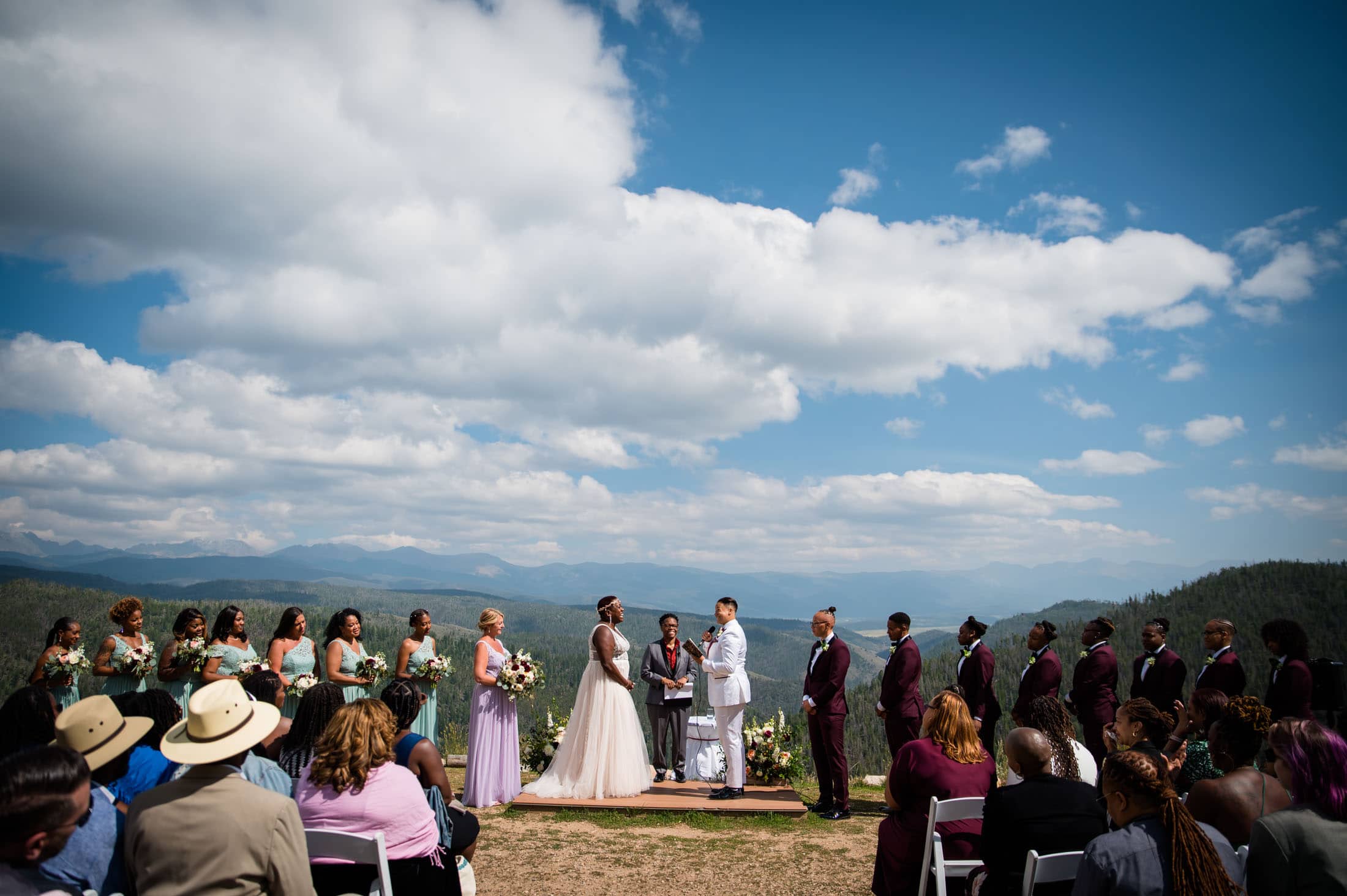 an LGBTQ+ couple says their vows in front of all their guests at their Granby Ranch ski resort wedding with views overlooking Mt. Audubon, Apache Peak and Mt. Jasper in the background.