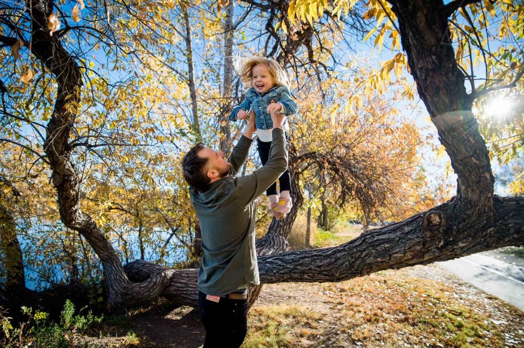 a father playfully tosses his toddler in the air at a park in Denver, Colorado