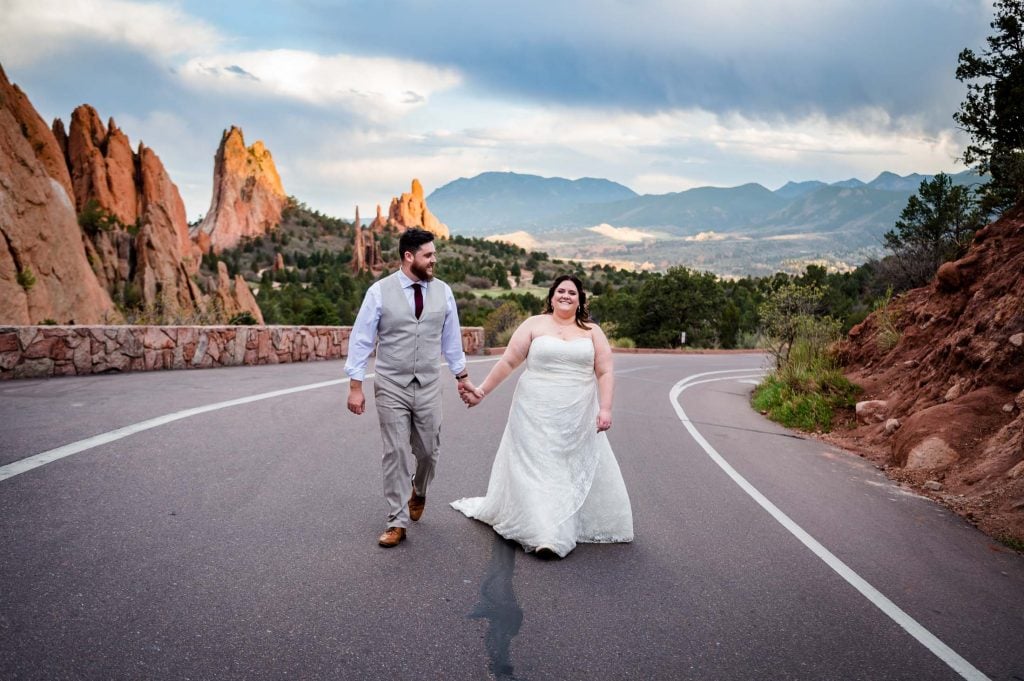 a marrying couple walks hand in hand on the road near Garden of the Gods after their intimate wedding ceremony