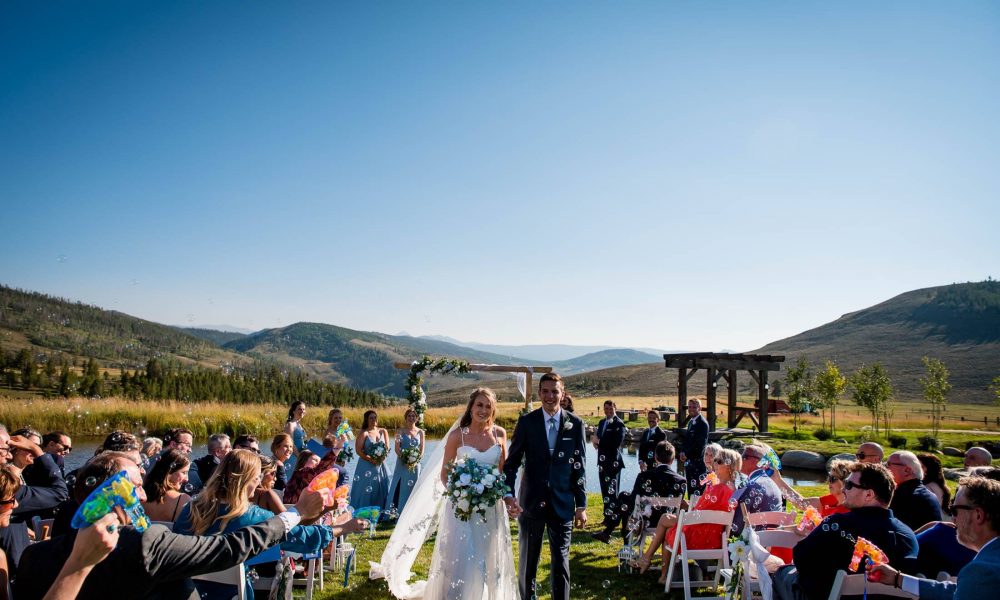 A couple walks back down the aisle with a bubble exit after their ceremony at Strawberry Creek Ranch near Granby, Colorado
