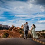 a couple walks hand in hand through Garden of the Gods for their engagement photography