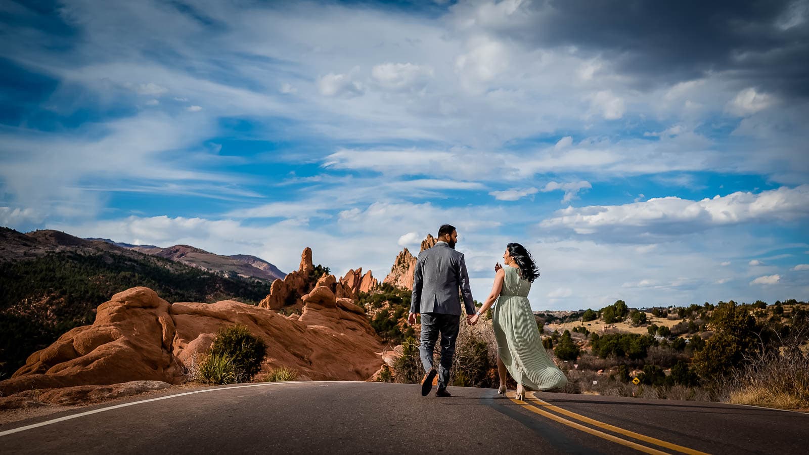 a couple walks hand in hand through Garden of the Gods for their engagement photography