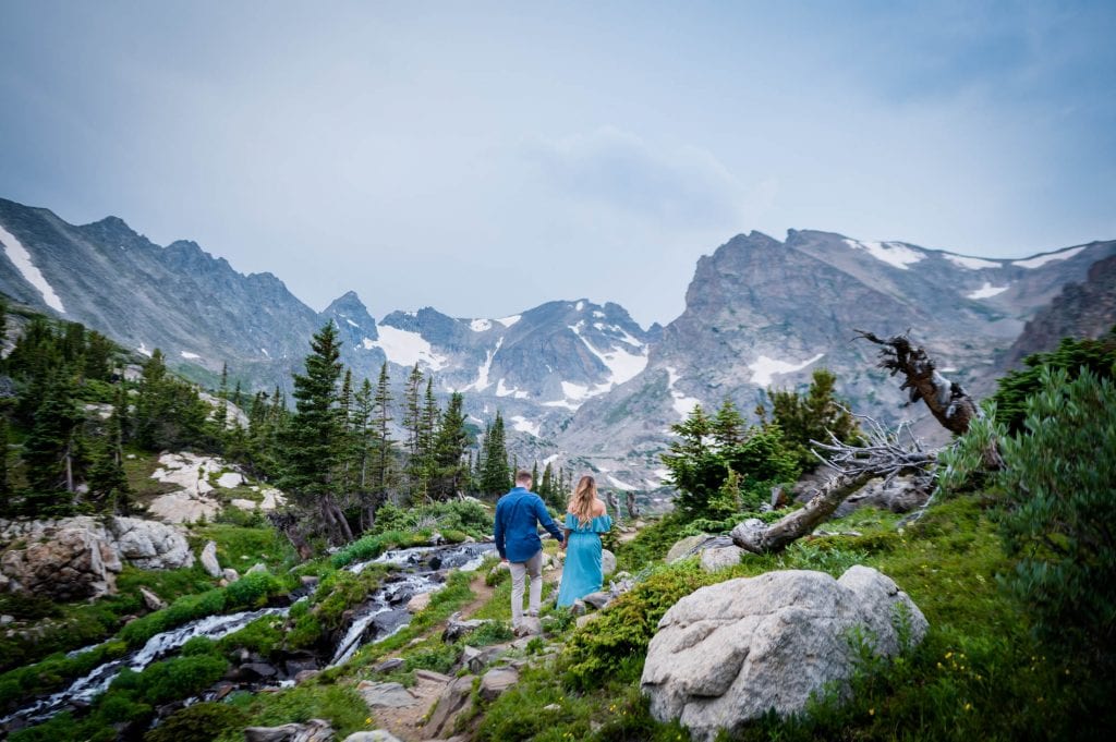 a couple hikes hand in hand towards Lake Isabelle for their elopement