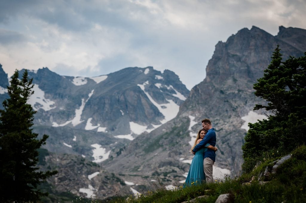 a couple hugs under the giant peaks in the indian peaks wilderness at their adventure engagement session in Colorado