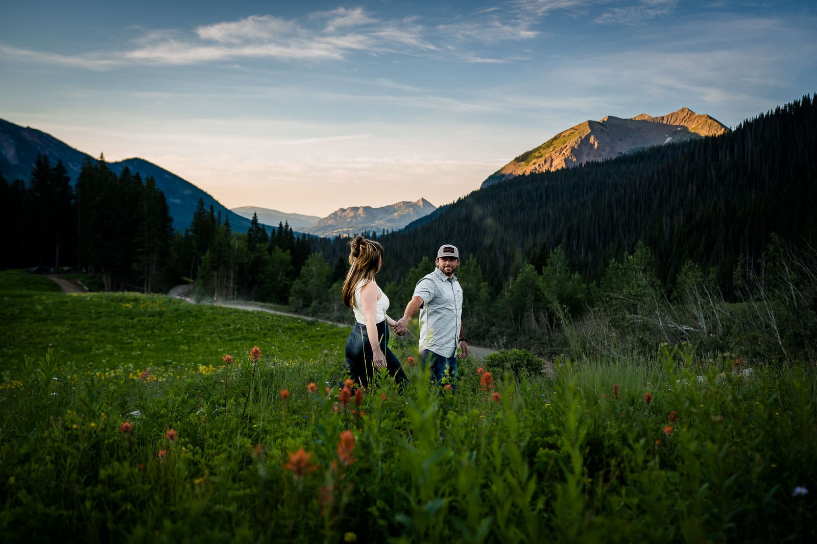 a couple walks through wildflowers in front of Mt Crested Butte in Colorado
