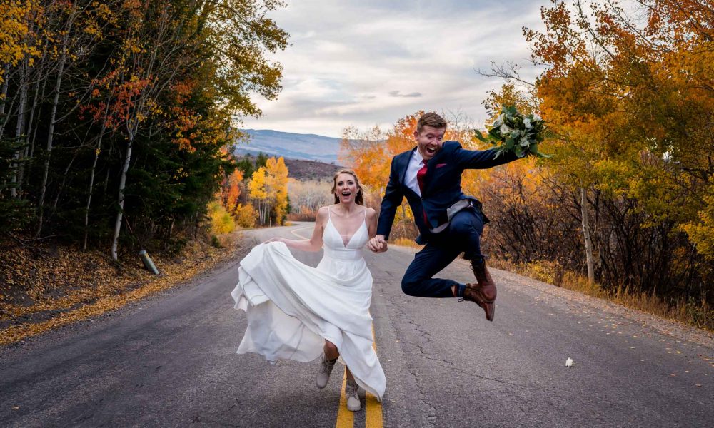 a couple runs down a back mountain road during fall in Colorado after their adventure elopement