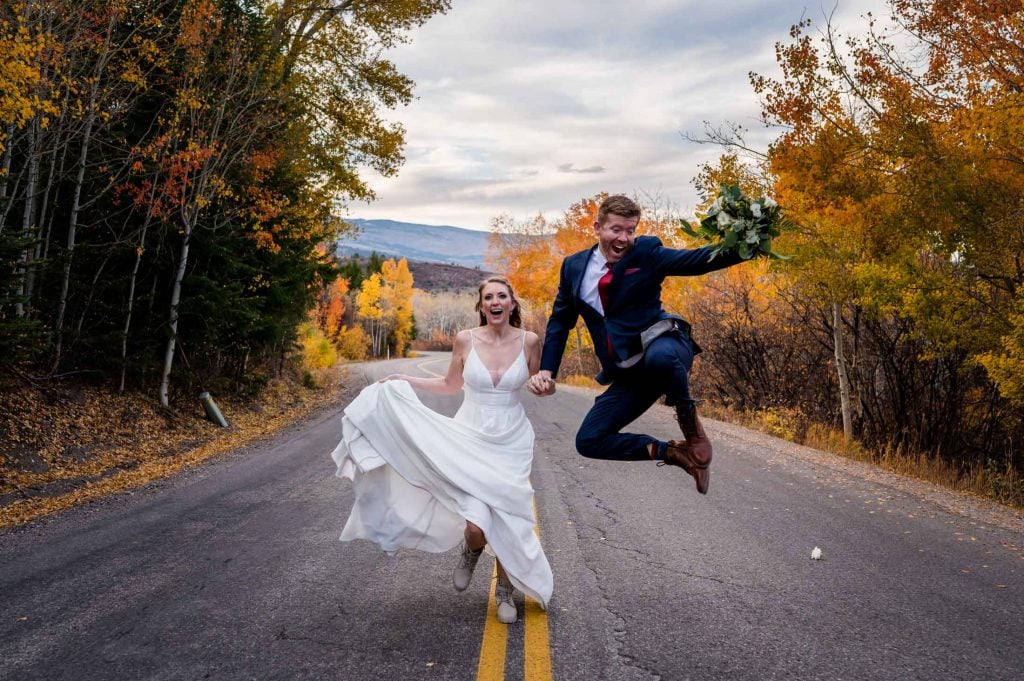 a couple runs down a back mountain road during fall in Colorado after their adventure elopement