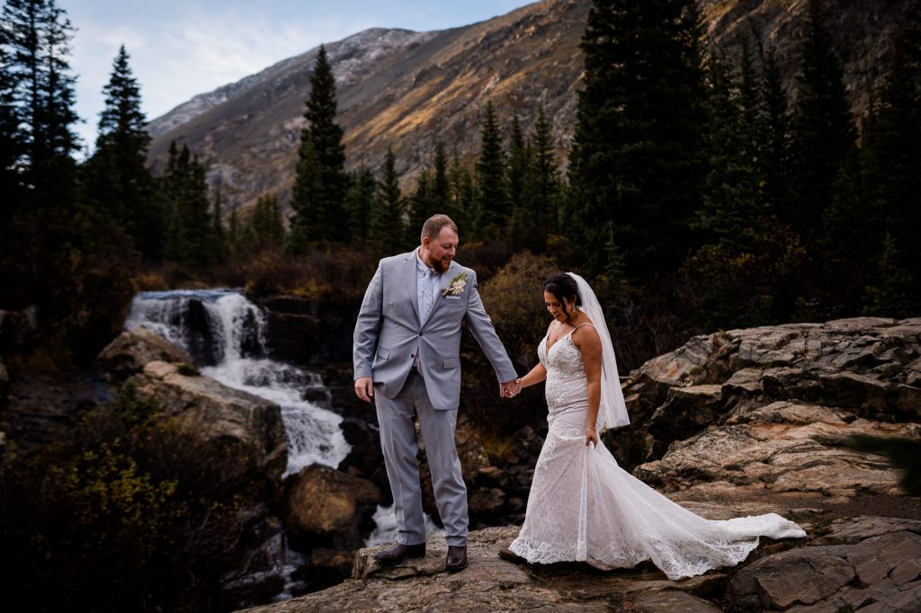 a couple explores a waterfall in Breckenridge Colorado for their adventure wedding