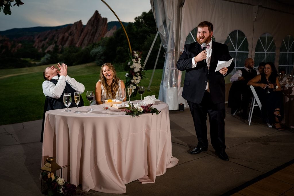 the best man makes the bride and groom laugh at their wedding during his speech at Arrowhead Golf Club at their Colorado wedding 