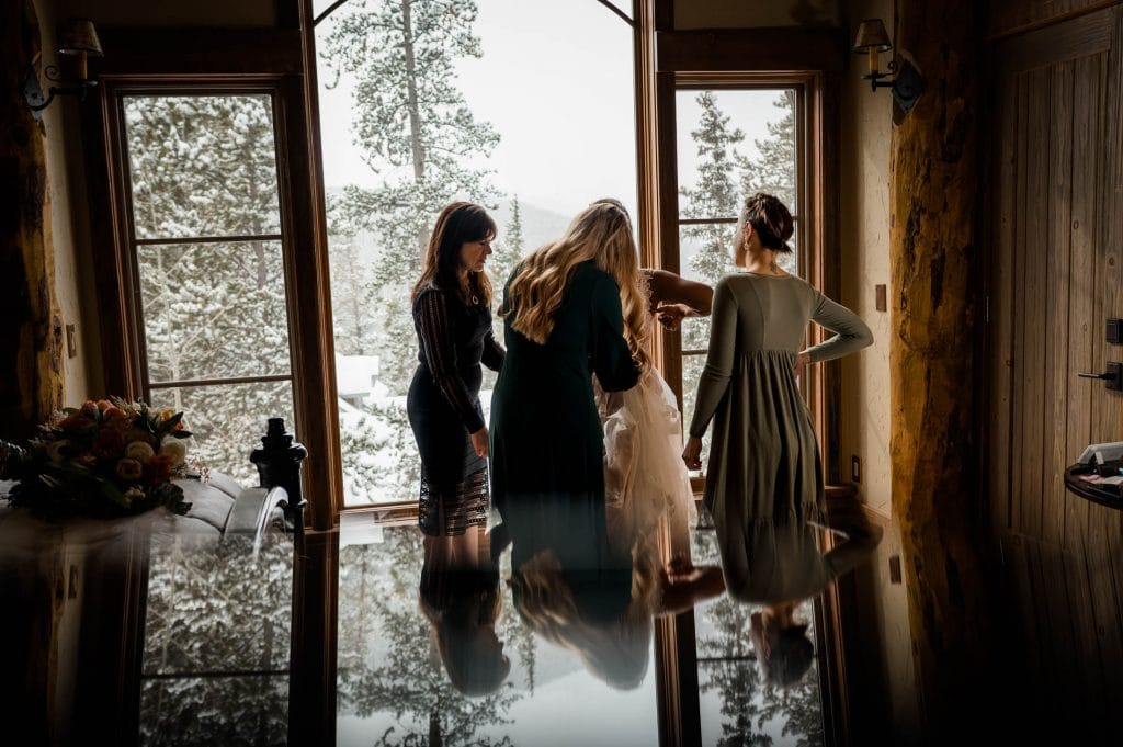 a bride gets dressed for her snowboarding elopement in Colorado