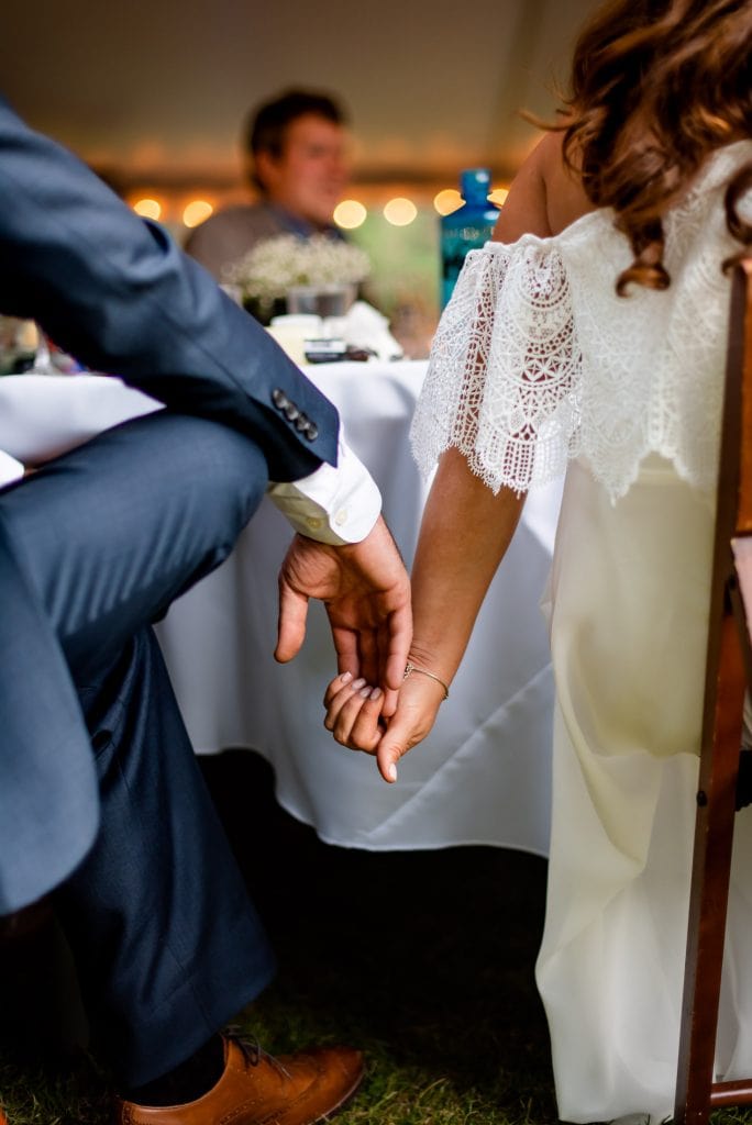 a couple holds hands as they listen to their closest family and friends give toasts at their intimate wedding in Estes Park