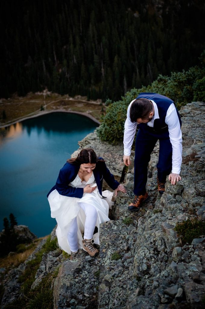 A couple hikes on a cliff together with their adventure gear. 