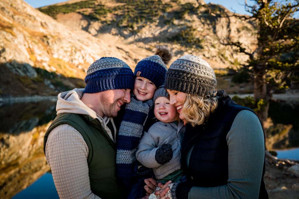 a family embraces at their Colorado adventure photo session in their custom knit hats, gloves and scarves. 