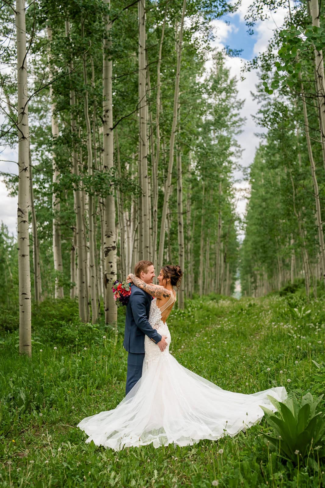 A couple snuggles in an aspen forest after their wedding ceremony at Black Mountain Lodge in Durango, CO