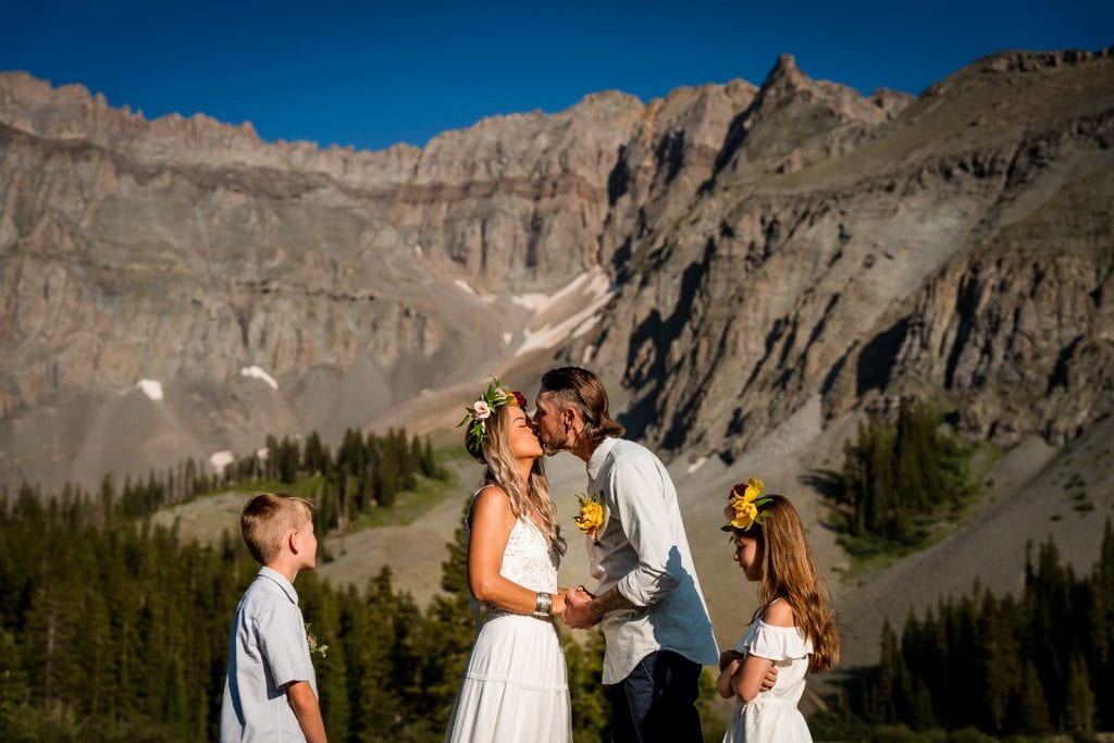 a couple kisses after their vows at their Colorado adventure elopement with their children