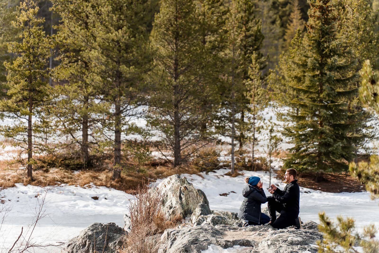 a man proposes to his partner on a rock outcropping in Summit County Colorado at Officers Gulch
